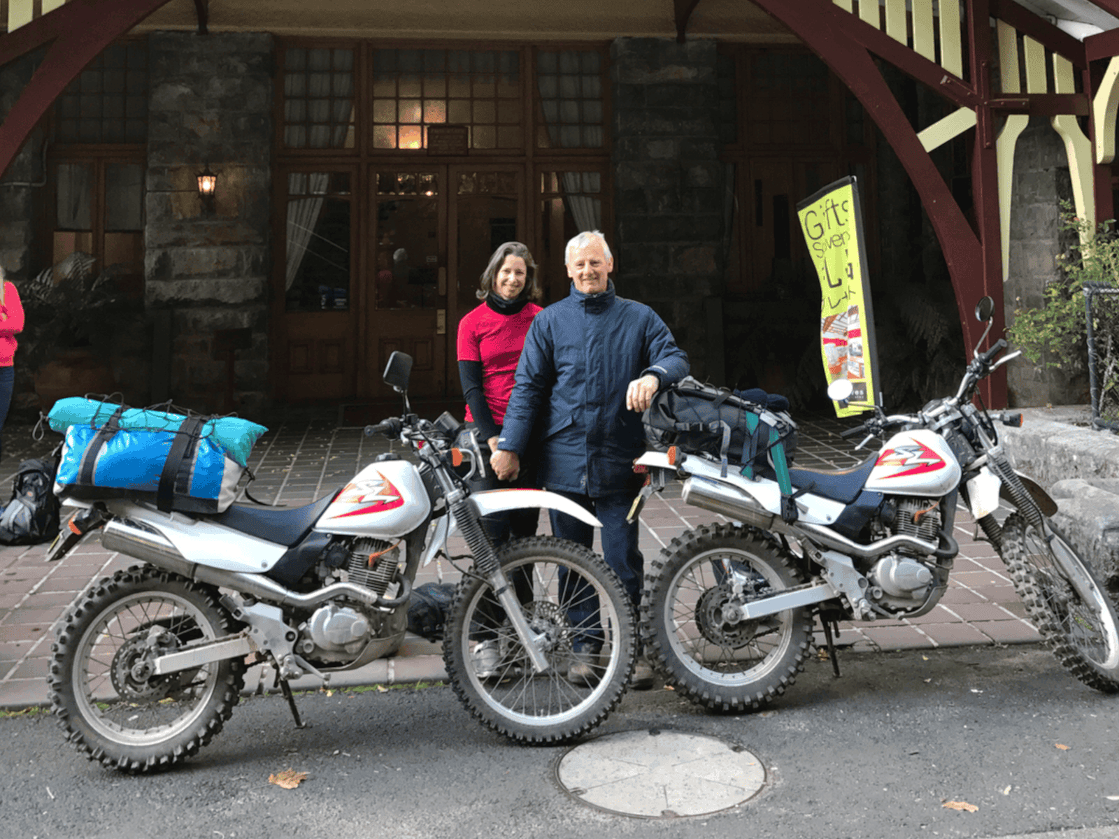 a couple with two motorbikes outside a hotel